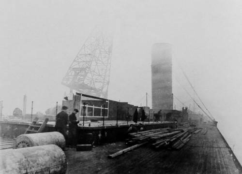 На RMS Olympic выполняют монтаж труб. Фото сделано из кормовой части на шлюпочной палубе судна. На фото мы видим уже вмонтированную третью дымовую трубу, а на переднем плане во всю кипит работа над установкой четвертой трубы